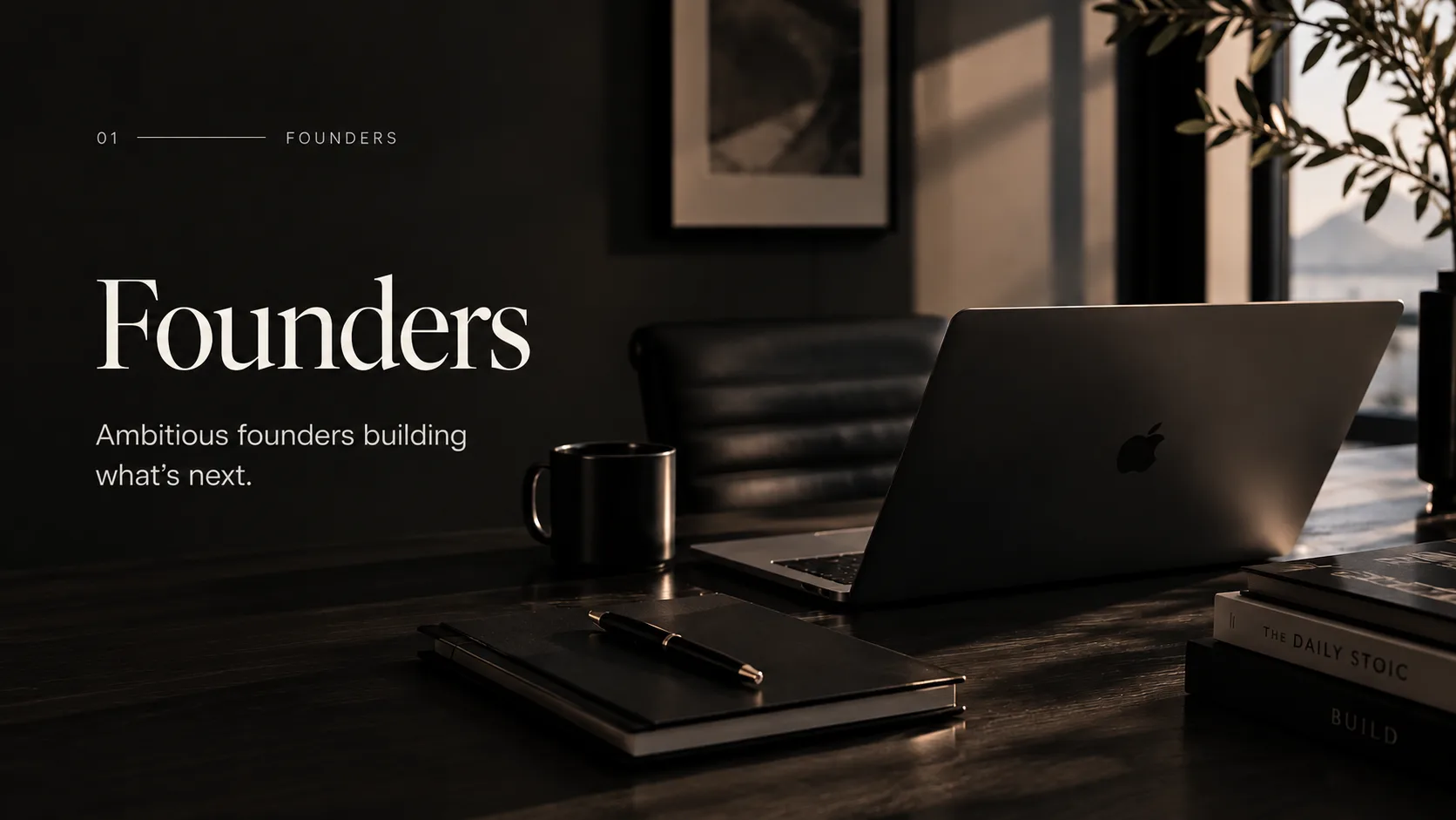 A considered, dimly lit founder's workspace with a laptop and notebook