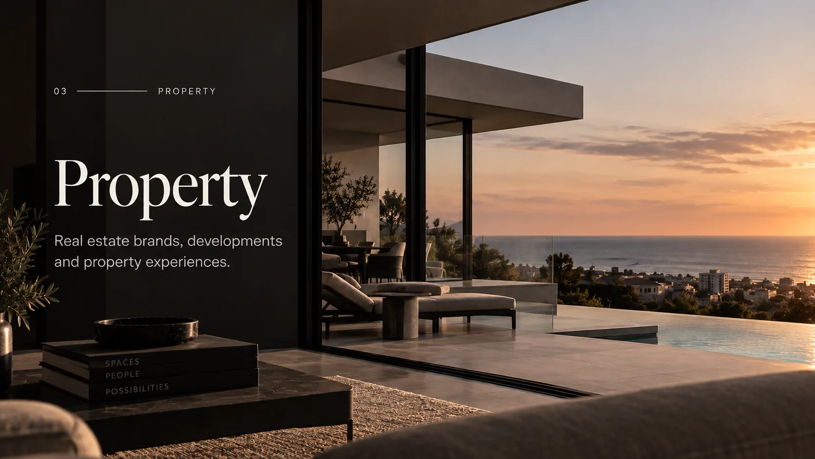 A modern home's terrace and infinity pool overlooking the coastline at sunset